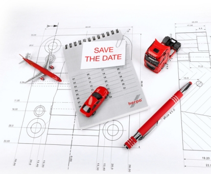 Herpa Veranstaltungen: Rotes Miniaturflugzeug, roter Miniatur-PKW und rote Miniatur-Zugmaschine auf Bauplänen. Mit rotem Kugelschreiber, Kalender und einem Save the Date Zettel